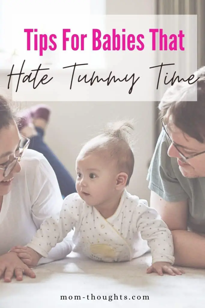 This image shows a picture of a mom and dad on the floor with their baby doing tummy time. The baby is in between the mom and dad. There is a white faded rectangle with text that says "Tips for babies that hate tummy time"