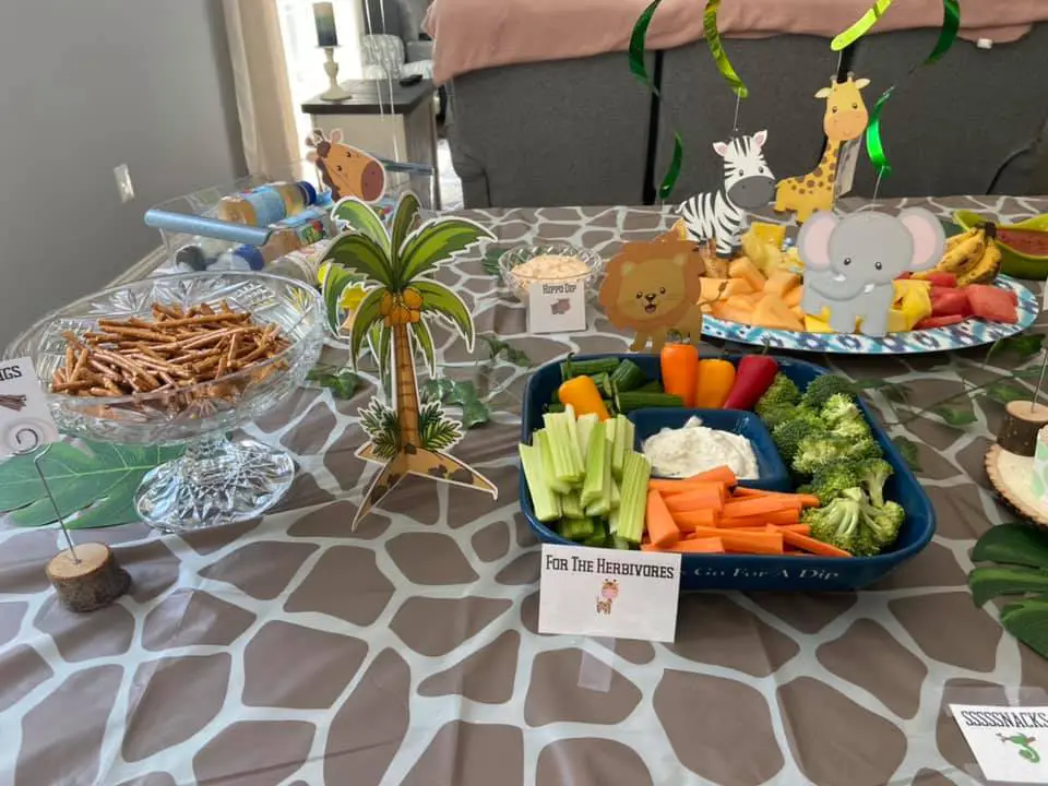 This image shows appetizers at a Young Wild and Three Birthday party. There are printable food labels. There's a giraffe print table cloth covering the table. 